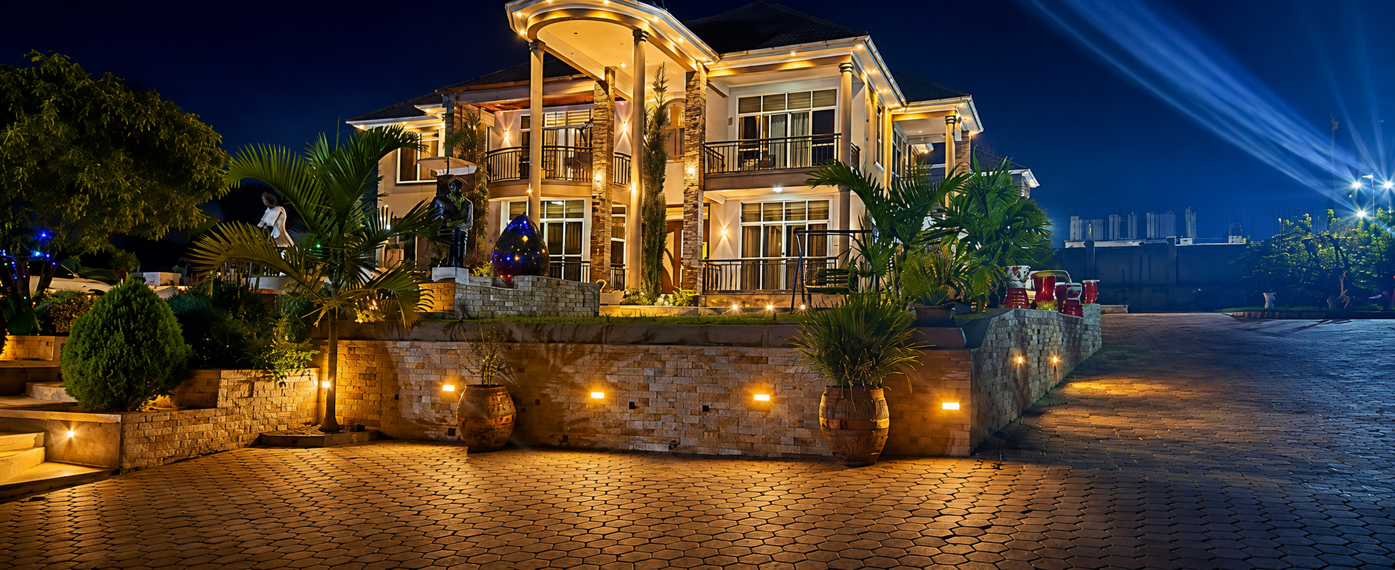 The Ddungu Residence illuminated at night, surrounded by gardens